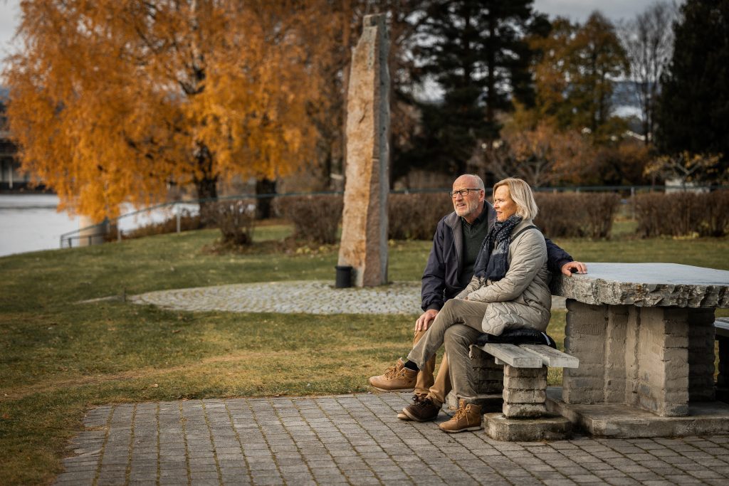 to voksne mennesker sitter på en benk i en park
