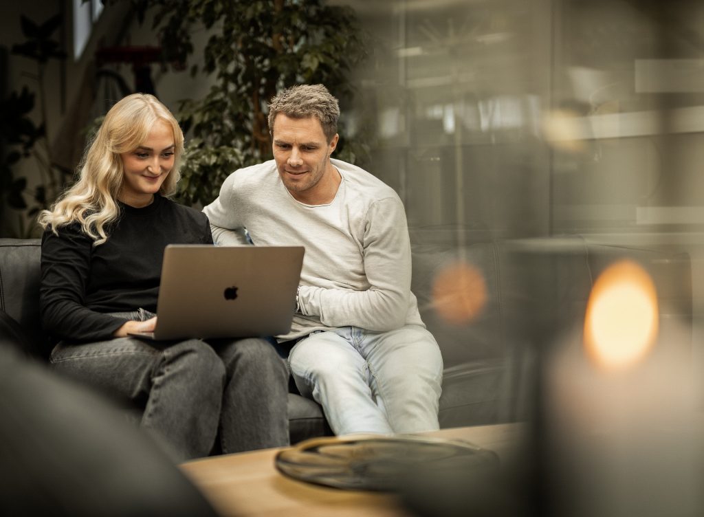 Ungt par sitter i sofa og ser på en PC