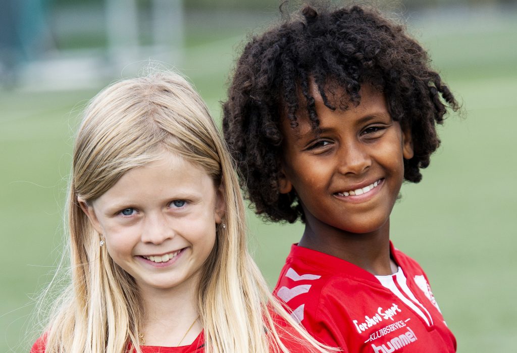To barn i fotballdrakt smiler