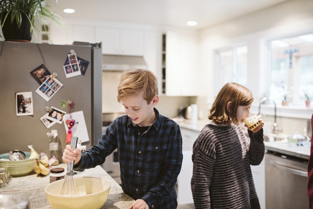 2 barn lager mat og drikker jus på kjøkken