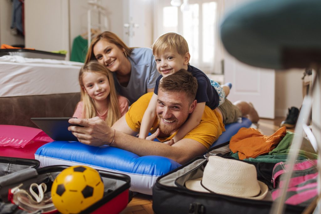 Familie på ferie - et hotellrom med kaos av flytemadrasser og klær.