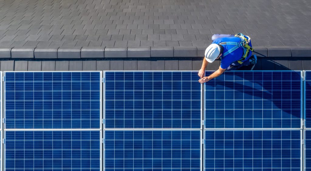mann på tak som setter opp solcellepanel