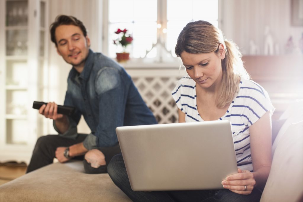 Mann og kvinne sitter med PC i stua