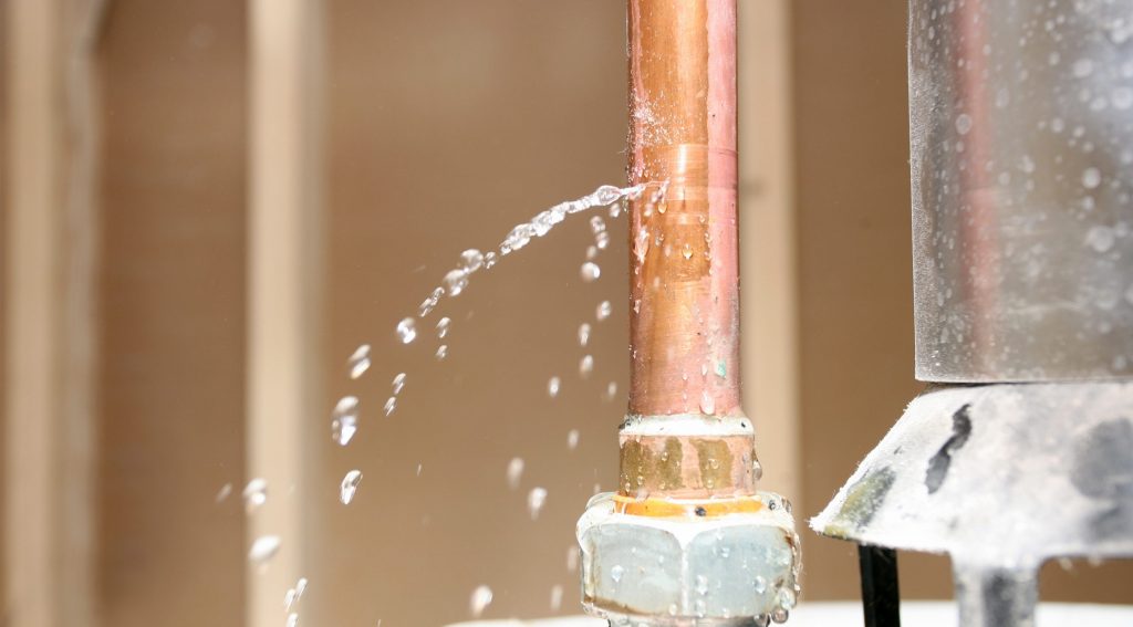 Et vannrør med sprekk der vannet pipler ut - vannlekkasje